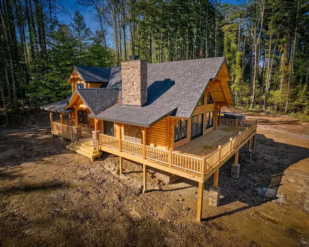 Beautiful log home with large deck surrounded by trees.