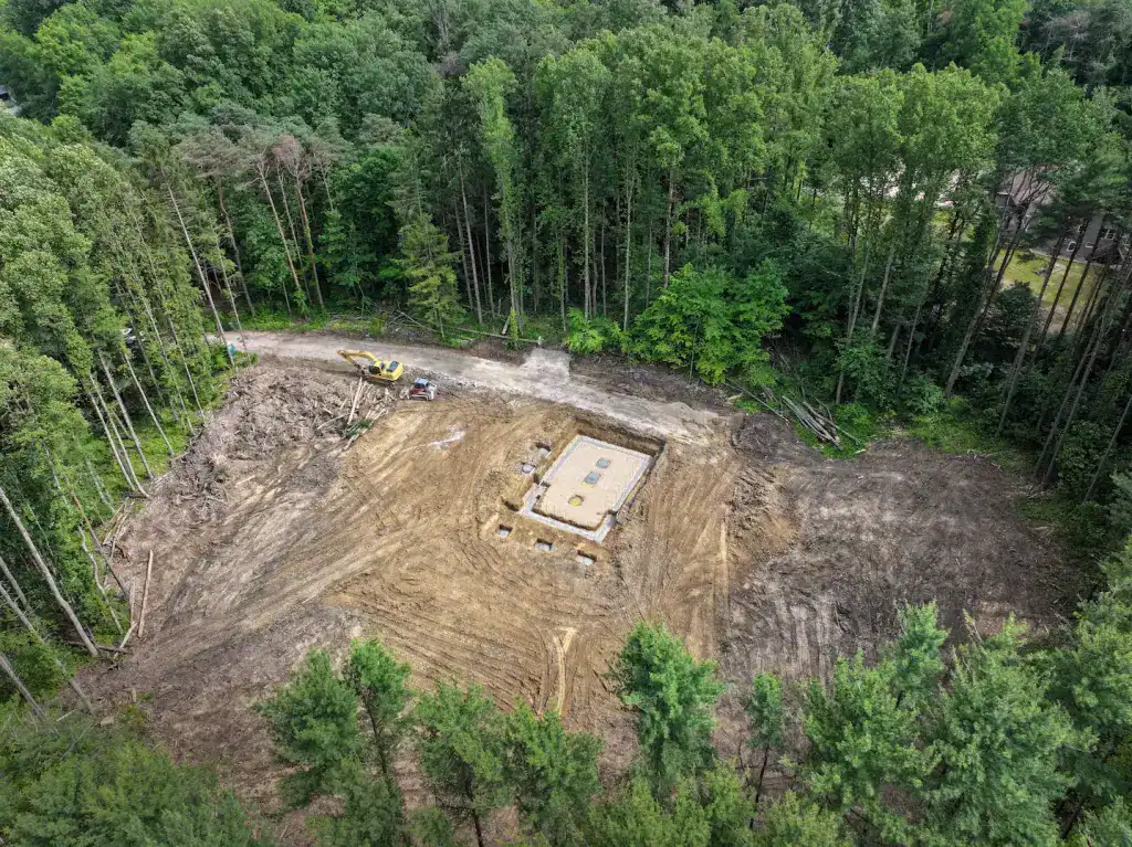 Construction site for a log home foundation in a wooded area.