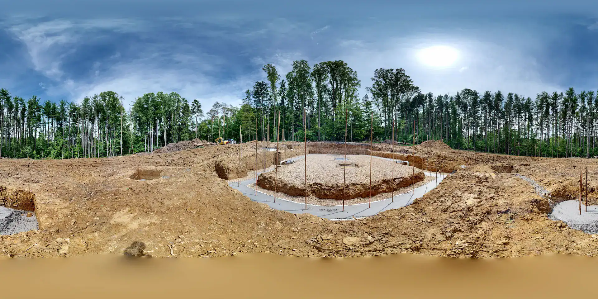 Excavation site for log home foundation with surrounding trees.