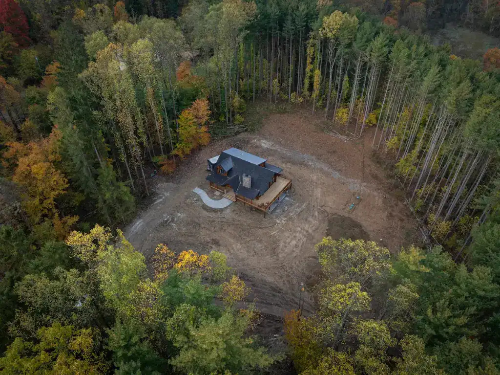 Aerial view of a log home under construction in a forested area.