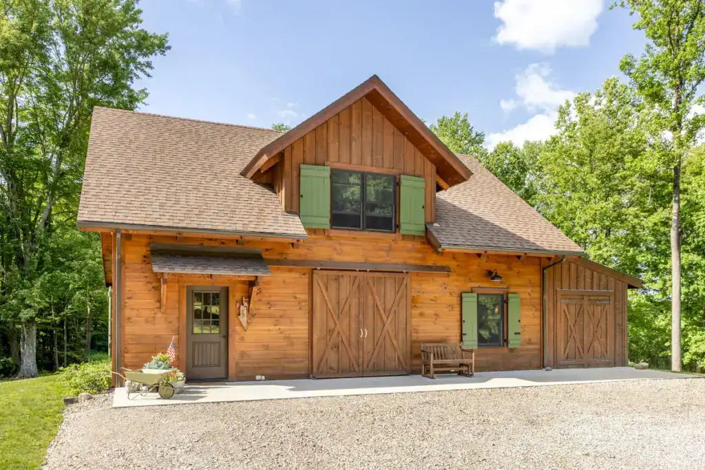 Square-log barn with green shutters and traditional sliding barn doors on Stacy and Dave’s Ohio property.
