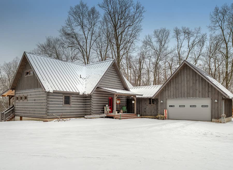 Beautiful log home with attached garage in a snowy landscape.