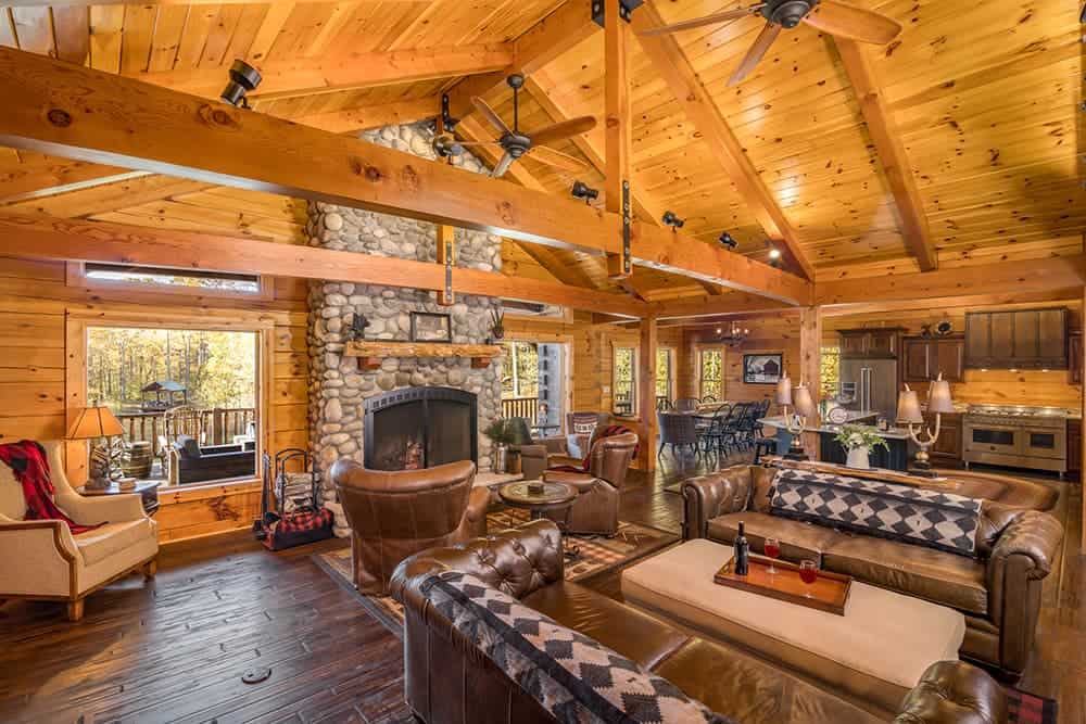 Cozy log home living room with stone fireplace and wooden ceiling.