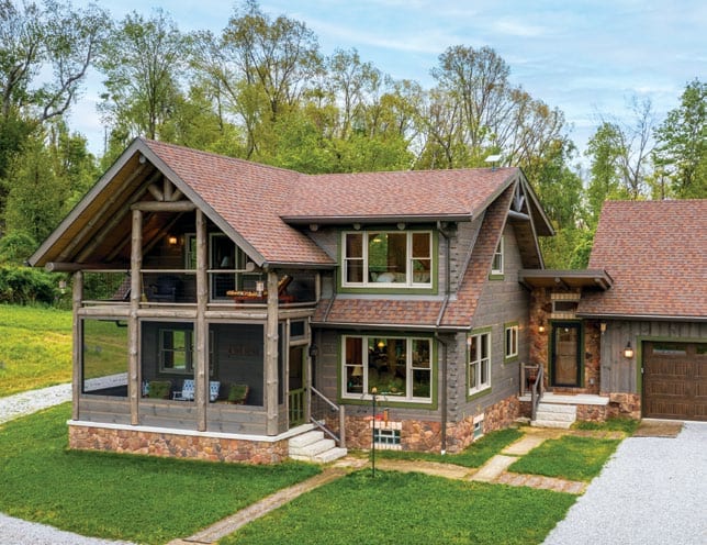 Beautiful log home with a spacious porch and lush green yard.