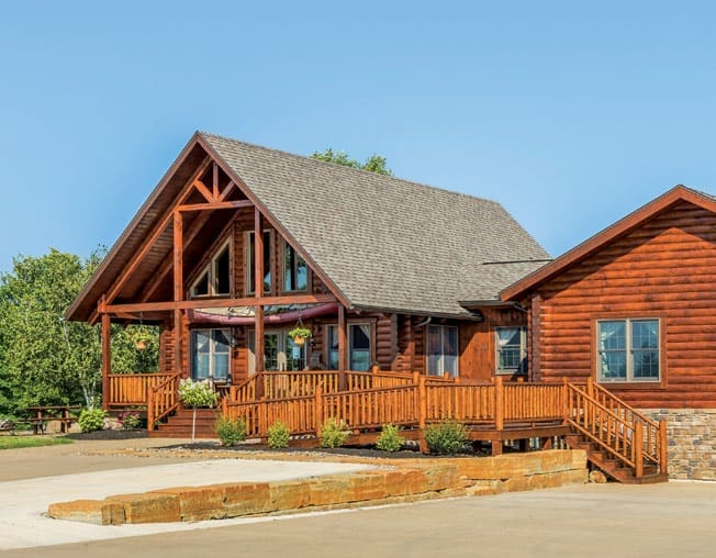 Beautiful log home with large porch and wooden accents in a scenic setting.