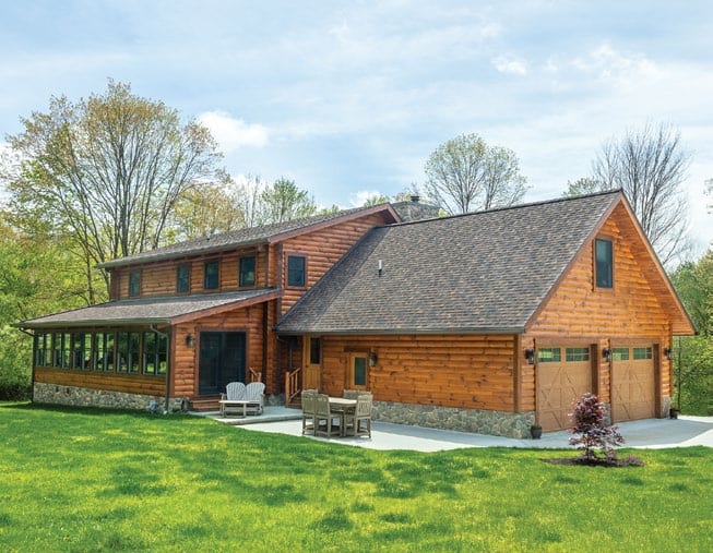 Beautiful wooden log home with a spacious yard and porch in a scenic setting.