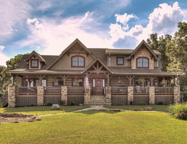 Beautiful log home with stone accents and spacious porch under a blue sky.